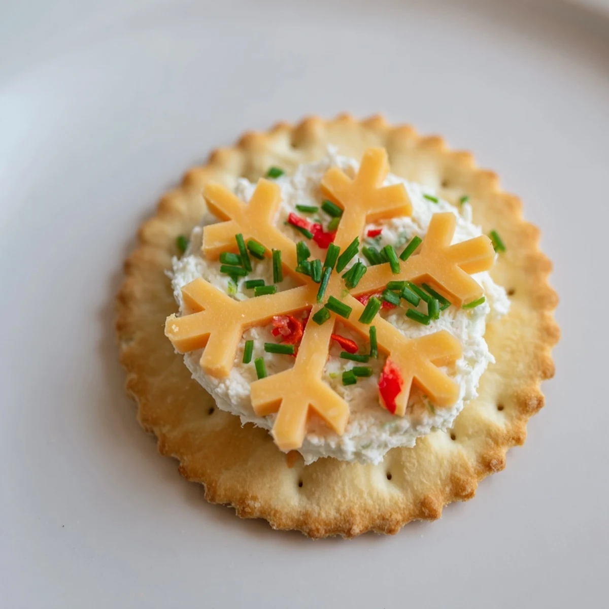 Creamy cheese snowflakes delicately arranged on crackers make these festive savory bites an elegant snack.