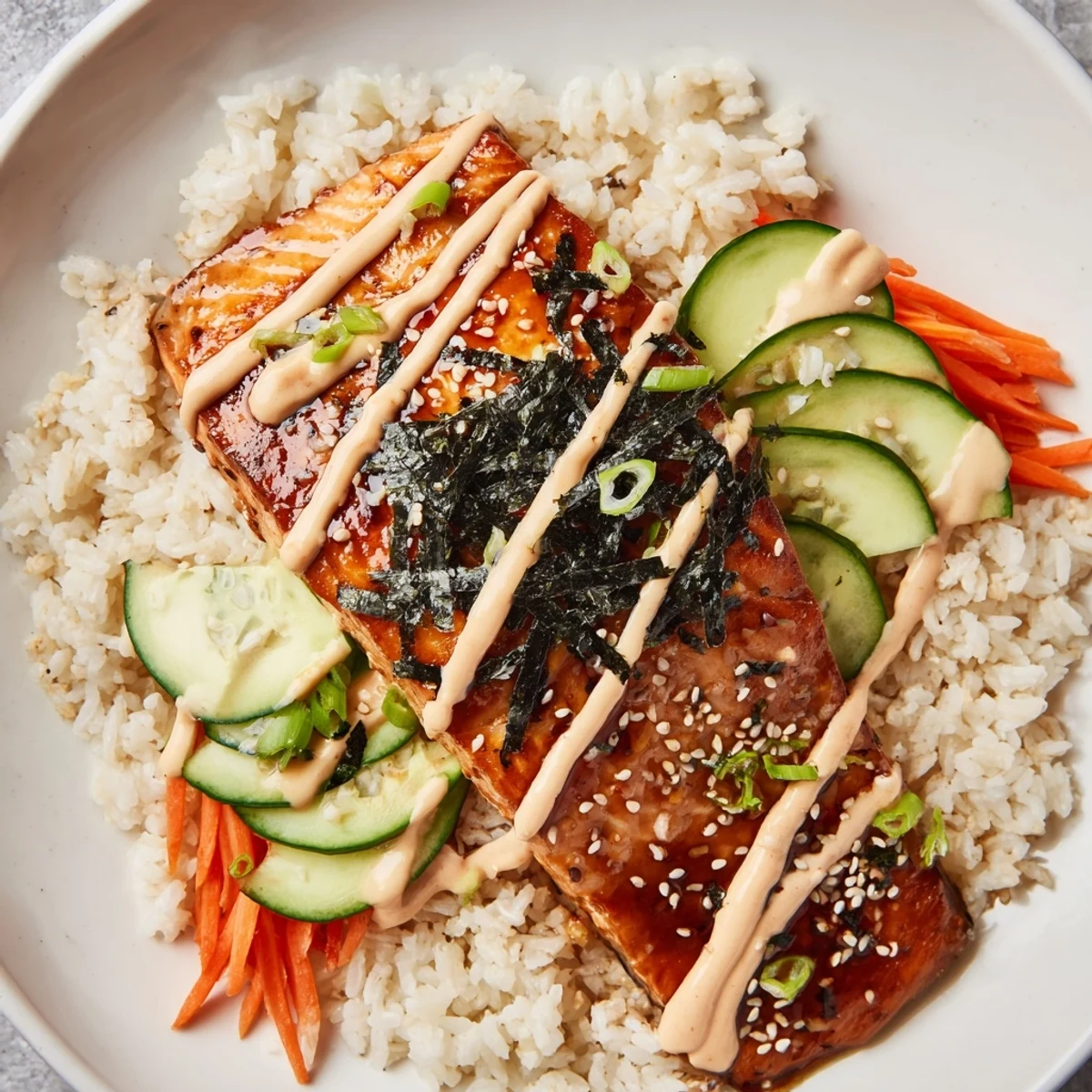 Golden, glazed teriyaki salmon rice bowl with colorful vegetables and creamy sriracha mayo.