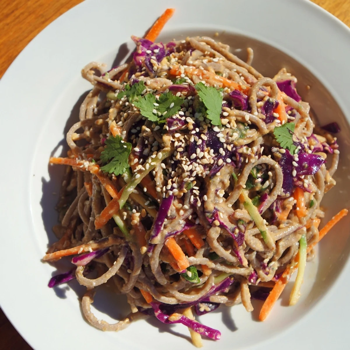 Vibrant soba noodle salad with colorful vegetables and a creamy sesame-peanut dressing, beautifully arranged.