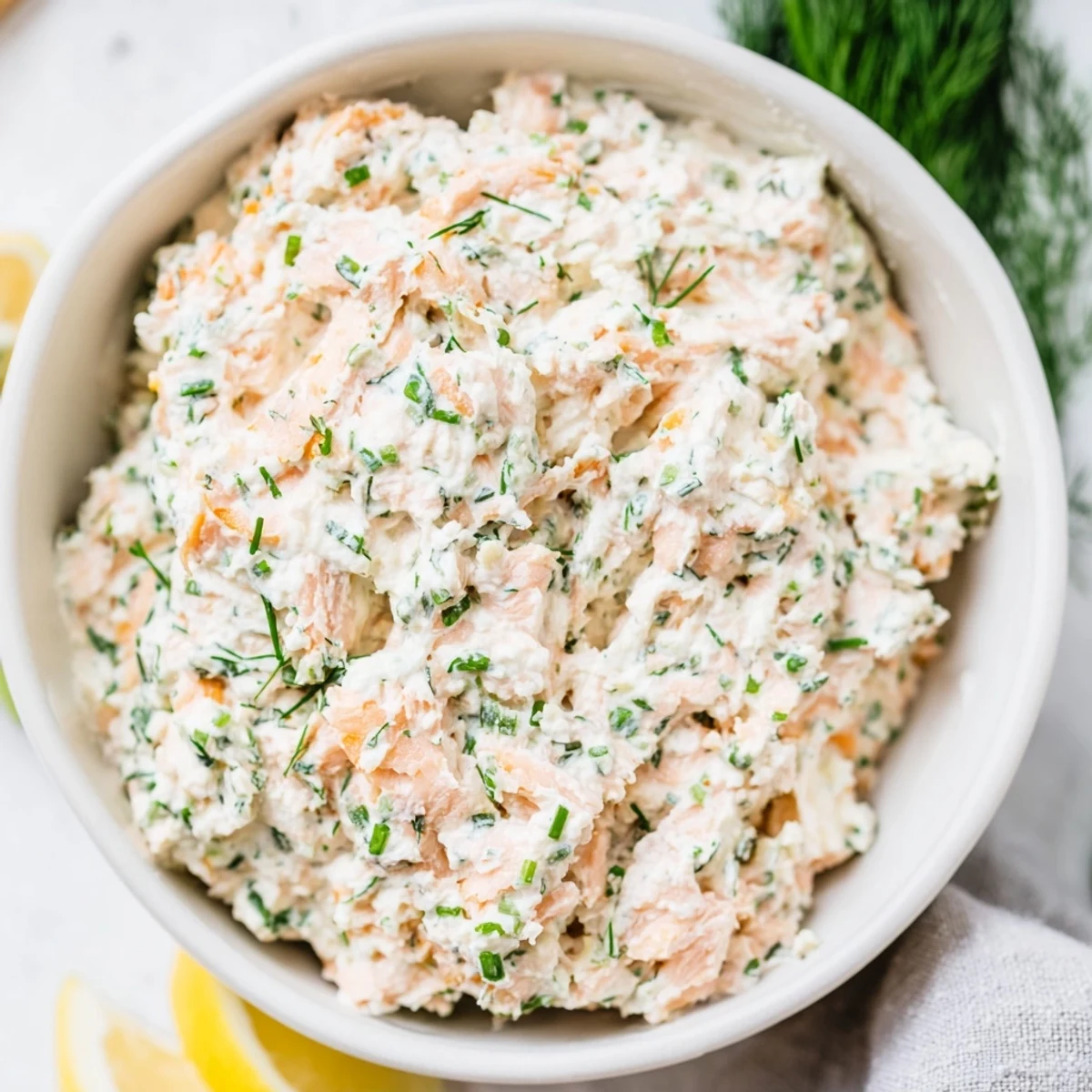 Creamy smoked salmon dip garnished with fresh dill and lemon wedges, served with crisp cucumber slices and rye crackers.