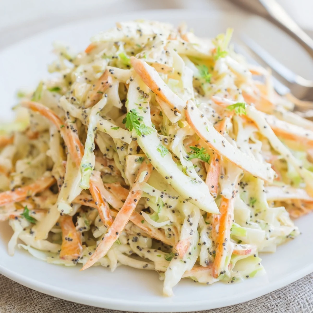 Shredded Green Cabbage and Apple Slaw served in a white dish, featuring crisp apples and carrots tossed in a tangy dressing.
