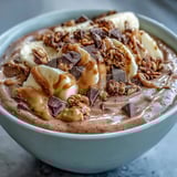 A creamy, thick breakfast bowl made with frozen banana, cocoa powder, and peanut butter, drizzled with extra nut butter.