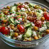 Served chilled, this High Protein Quinoa & Chickpea Salad looks fresh on a white plate with a fork.