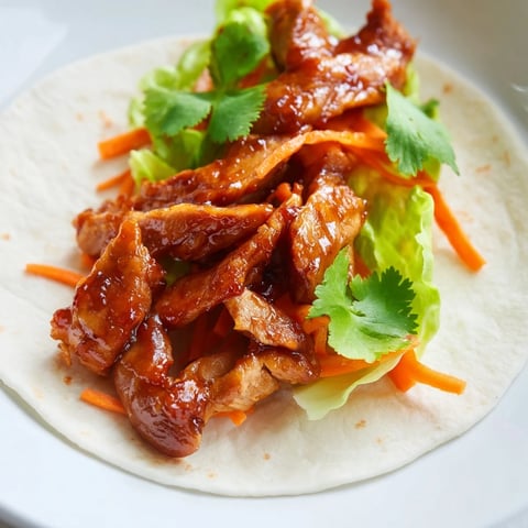 Close-up of Honey Sriracha Chicken Wrap sliced in half, showing tender glazed chicken and crisp vegetables inside a soft tortilla.  