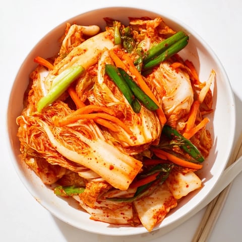 Bright red napa cabbage kimchi packed in a glass jar, showcasing crunchy fermented vegetables infused with gochugaru and garlic for a classic Korean side dish.