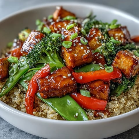 Golden crispy tofu cubes and vibrant stir-fried vegetables sit atop fluffy quinoa, drizzled with glossy teriyaki sauce in the Quinoa Vegetable Teriyaki Bowl.