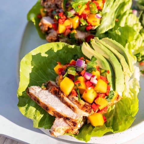 Vibrant image of chicken and mango salsa lettuce wraps, filled with juicy chicken and colorful veggies.