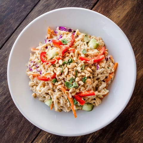 A close-up of a Spicy Peanut Noodle Salad, showing fresh cilantro and sesame seeds on top.
