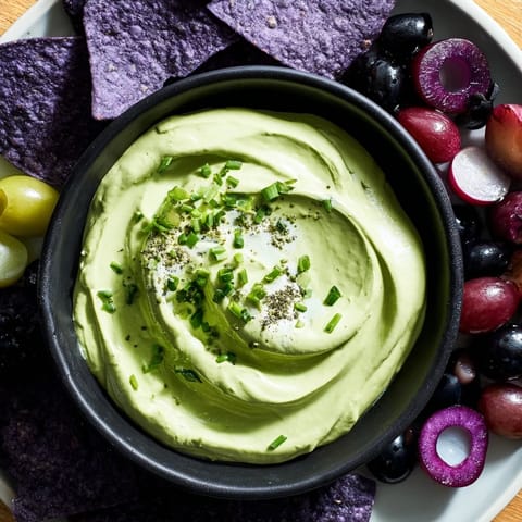This Witch's Brew Cauldron appetizer shows a bubbling green dip with dark, smoky-looking garnishes around it.