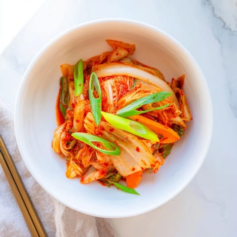 Homemade kimchi fermenting in a jar with vibrant orange carrots and white daikon radish, offering a tangy, spicy crunch perfect for rice bowls.