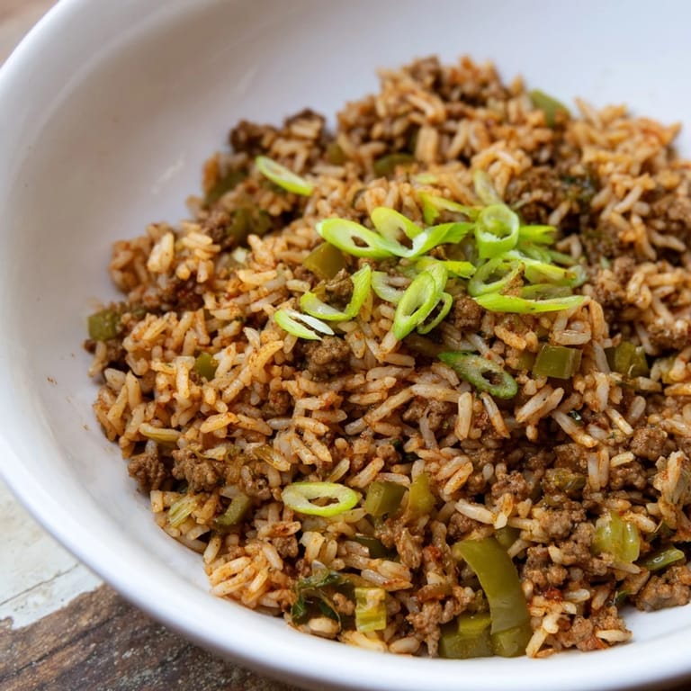 Close-up of a rustic serving of Cajun Dirty Rice, garnished with fresh spring onions for a pop of color.