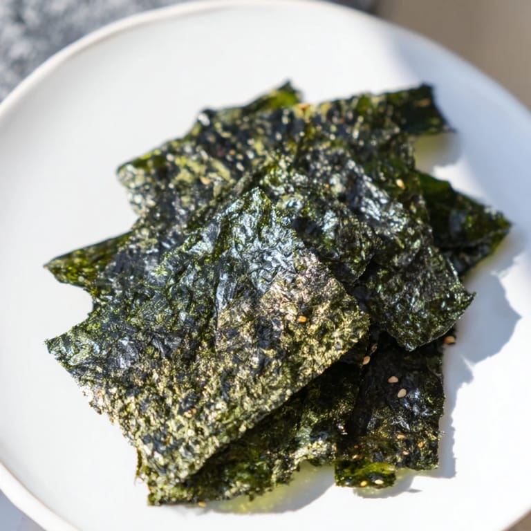Thin, crispy roasted seaweed chips with a deep green hue and a delicate, salty sesame finish.