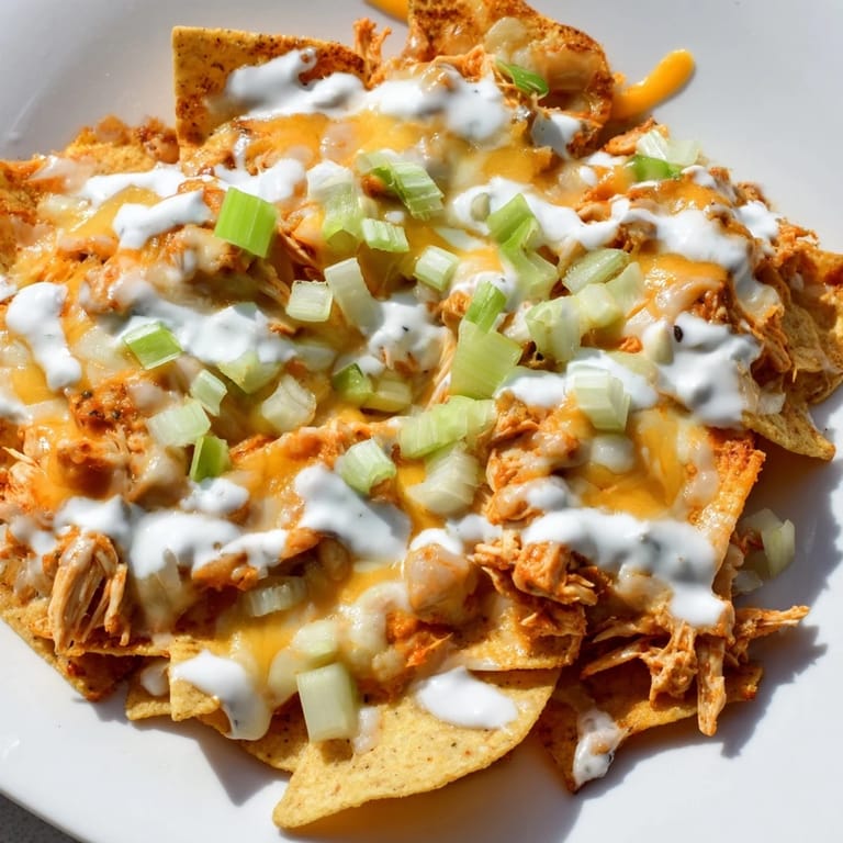 Sizzling Buffalo Chicken Nachos loaded with spicy shredded chicken, plenty of cheese, and fresh toppings on a platter ready for sharing.