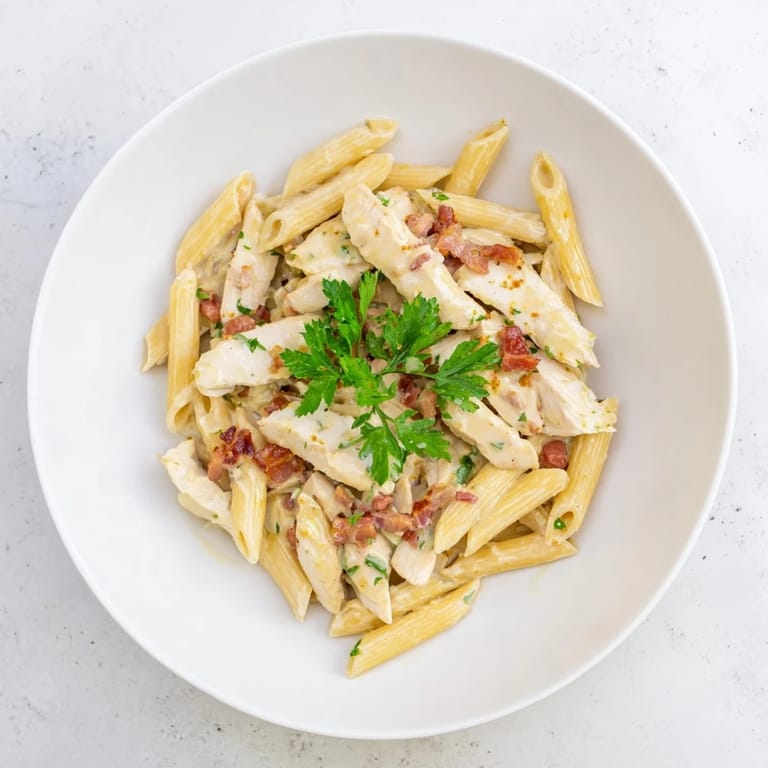 A warm skillet of Creamy Chicken Bacon Penne garnished with fresh parsley, ready to serve alongside a crisp green salad.