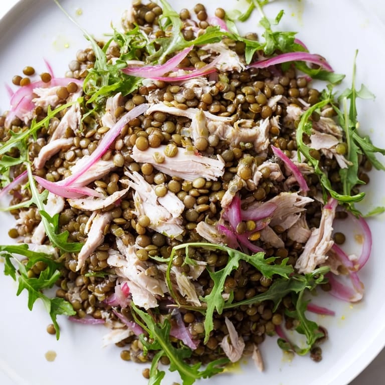 A vibrant bowl of Lentil & Chicken Spring Salad featuring peppery greens, pickled onions, and cherry tomatoes for a refreshing, protein-packed meal.