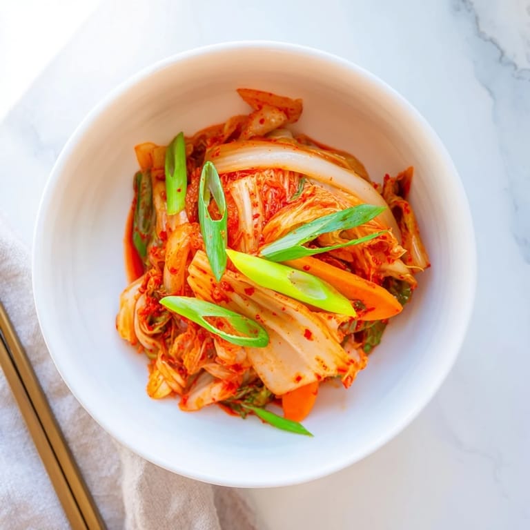 Homemade kimchi fermenting in a jar with vibrant orange carrots and white daikon radish, offering a tangy, spicy crunch perfect for rice bowls.
