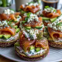 A vibrant spring brunch spread with smoked salmon, assorted bagels, and creamy herb cream cheese on a large wooden board.