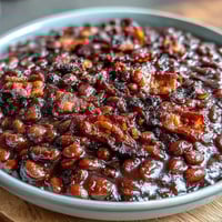 A bubbling casserole of baked beans with crispy bacon, sweet brown sugar, and smoky paprika, fresh from the oven.