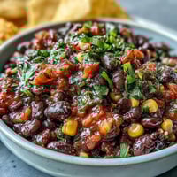 Vibrant 3-ingredient cowboy caviar dip with black beans, corn, and fresh pico de gallo, perfect for scooping with tortilla chips.