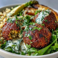 Spring Buddha Bowl with roasted asparagus, radishes, and crispy falafel, drizzled with lemon tahini dressing.  